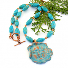 The unique SITHEIL handmade necklace features an artisan made woman's face pendant, turquoise magnesite ovals and copper - unique jewelry gift for her. distressed terracotta face pendant necklace handmade turquoise magnesite copper